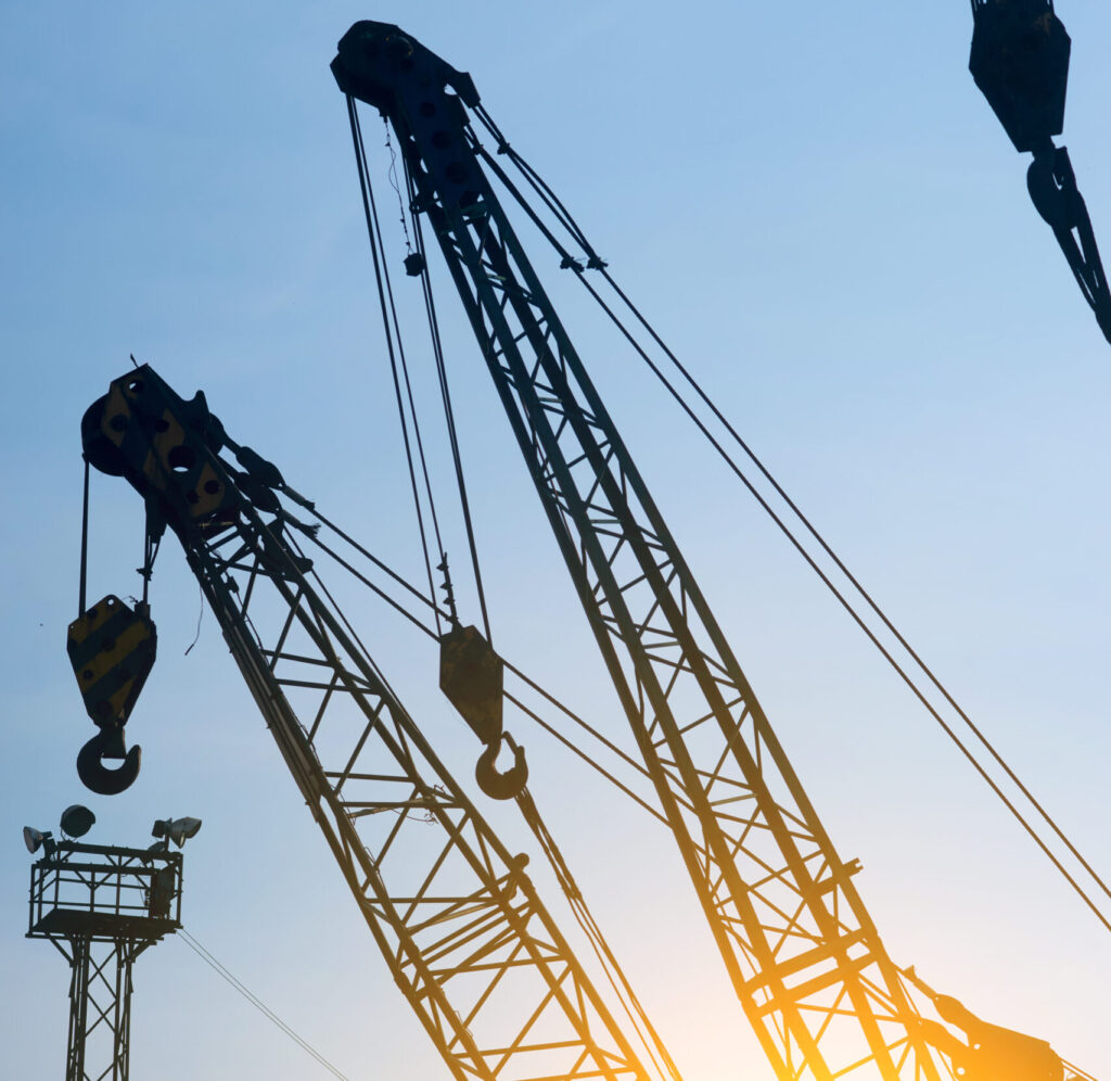Cranes silhouetted against sky.